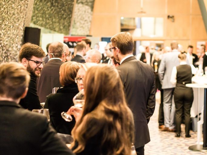 Business event A group of people in formal attire socialising at an indoor event.